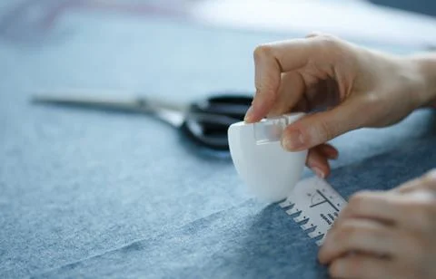 Closeup of skilled tailor hands marking and measuring fabric while making Stock Photos