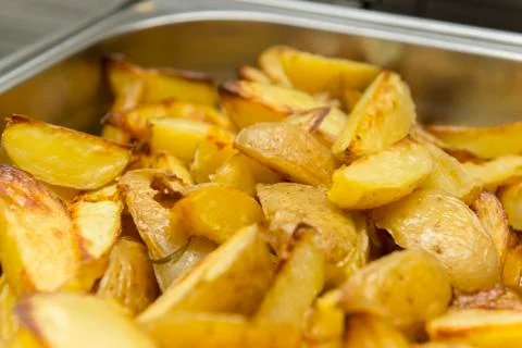 Closeup of sliced and baked rustic potatoes. Tasty dish to be served at dinne Stock Photos