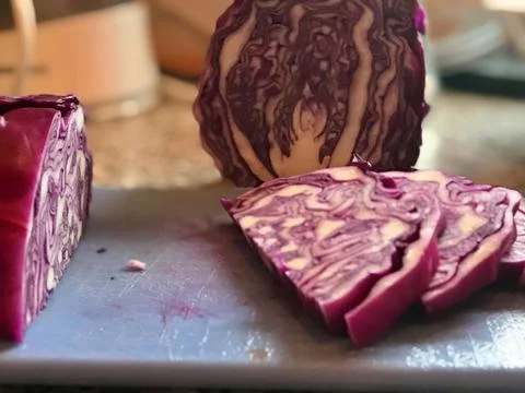Closeup of sliced red cabbage on blue plastic cutting board on the kitchen count Stock Photos