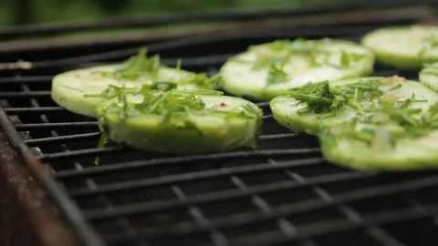 Closeup sliced vegetable marrow are being cooked on the bbq grill during the day Stock Footage 213996407