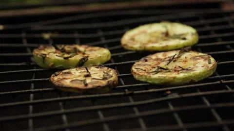 Closeup sliced vegetable marrow are being cooked on the bbq grill during the day Stock Footage 213997091