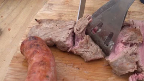 Closeup slicing medium cooked beef on the grill with knife on a wooden board in 库存影片 155808969