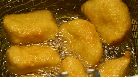 Closeup slow motion crispy fried chicken meat nuggets deep frying in boiling oil Video stock 289303508
