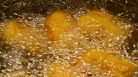 Closeup slow motion crispy fried chicken meat nuggets deep frying in boiling oil Video stock 290069485