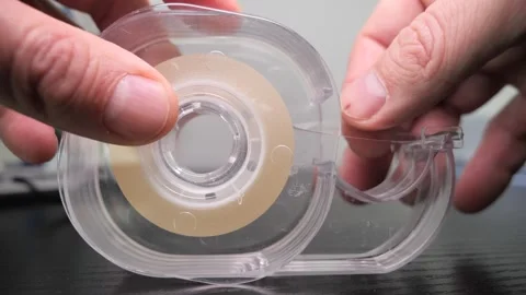 Closeup slow-motion of human hand using Adhesive Tape Dispenser on black table Stock Footage 266042059