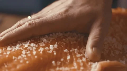 Closeup slow motion of piece of fresh salmon placed on hot cooktop and sprinkled Stock Footage 154730656