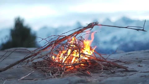 Closeup slow motion shot of bonfire in front of the snow covered mountains Stock Footage 228190198