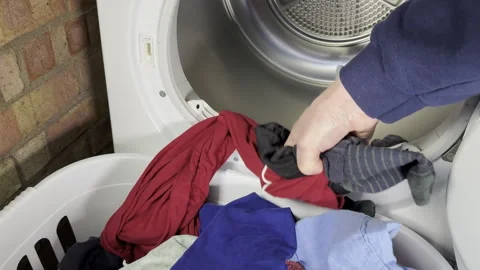 Closeup slow motion shot of a man emptying a tumble dryer. Stock Footage 299990977