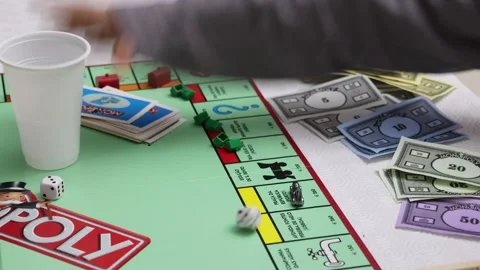 Closeup slow motion shot of a person rolling dice over a Monopoly board Stock Footage 271048852