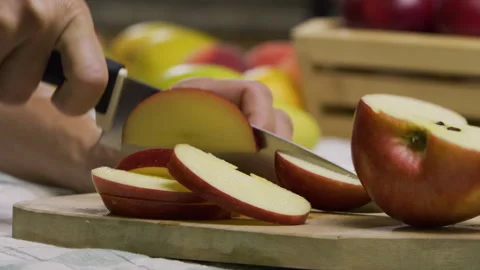Closeup, slow motion shot of sharp knife slicing up apple on cutting board Stock Footage 341228112