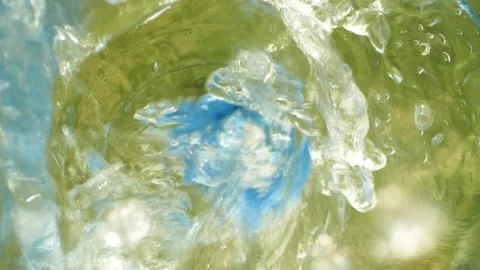 Closeup slow motion water falling down from bottle with drops splashing on grass Stockbeeldmateriaal 154229495