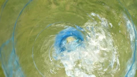 Closeup slow motion water falling down from bottle with drops splashing on grass Stock Footage 154229539