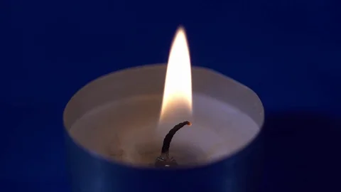 Closeup of a small candle burning on the blue background Stock Footage 76194074