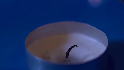 Closeup of a small candle lighting up on the blue background slow motion Stock Footage 76194010