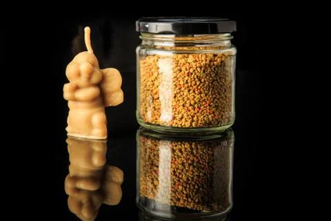 Closeup small jar with bee pollen and bee shape wax candle Stock Photos