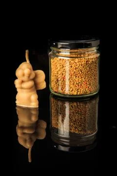 Closeup small jar with bee pollen and bee shape wax candle Stock Photos