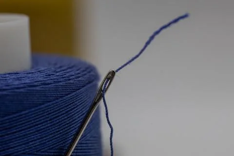 Closeup of a small needle in a blue thread on the blurry background Stock Photos