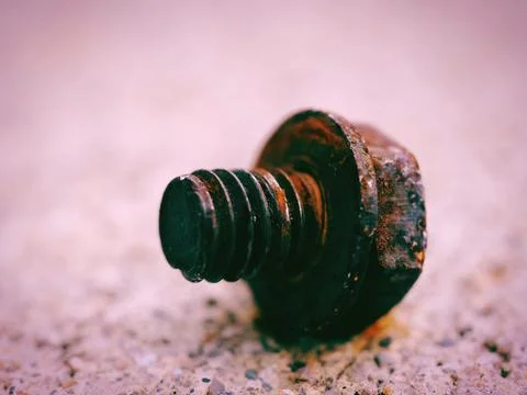 Closeup of a small rusty bolt isolated on a bumpy background 스톡 사진