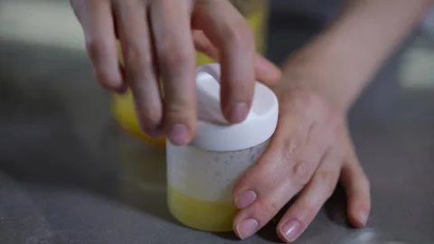 Closeup of a small, transparent plastic container filled with a vibrant yellow  Stock Footage 301437395