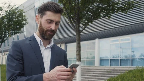 CloseUp of Smiled Bearded Businessman using his Smartphone and Smiles.  Stock Footage 113276864