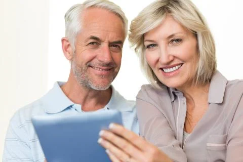 Closeup of a smiling mature couple using digital tablet Stock Photos