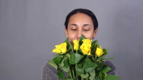Closeup of smiling mixed-race young pretty woman with bunch of yellow roses 스톡 동영상 146019060