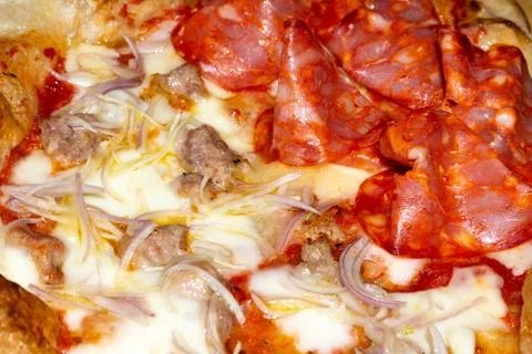 Closeup of soft pizza topped with tomato mozzarella salami sausage onion Stock Photos