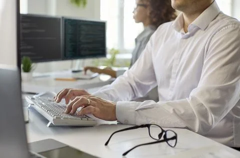 Closeup of software developer typing at keyboard in bright office, coding focus Stock Photos
