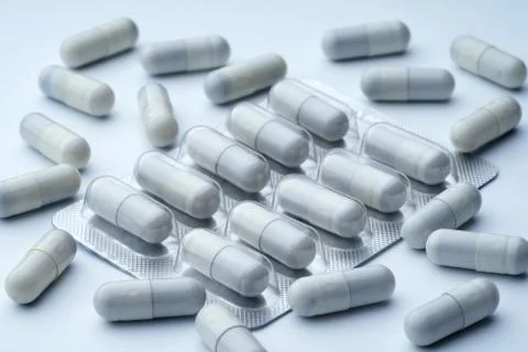 Closeup of some  gray pills in packaging on a white background with texture. Stock Photos