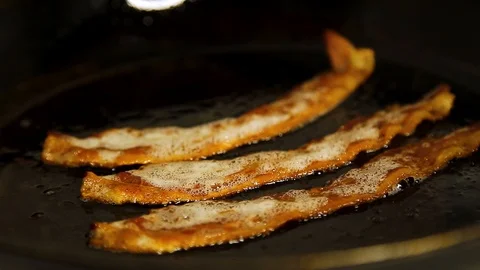 Closeup of some tasty strips of bacon frying in a pan in slow motion. HD 24FPS. Stock Footage 124397243