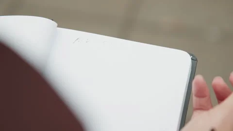 Closeup of someone composing on paper outside during calm day. Contemplative Stock Footage 341770858