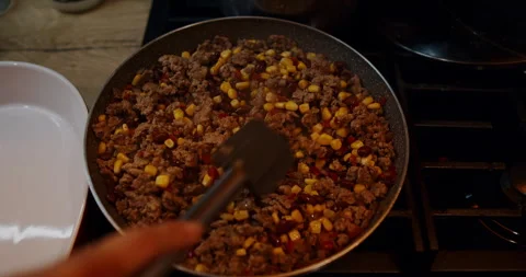 A closeup of someone cooking ground beef, corn, and beans in a pan Stock Footage 307935425