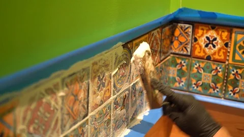Closeup of a spatula float applying grout to colorful tiles. Stock Footage 101434694