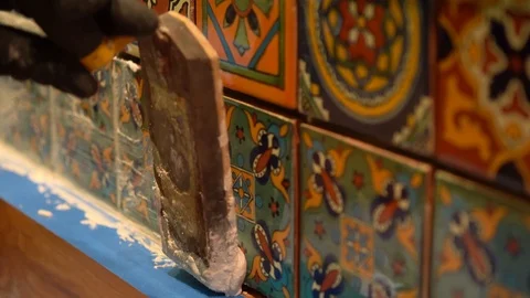 Closeup of spatula float pressing wet grout in between colorful tiles. Stock Footage 101434708
