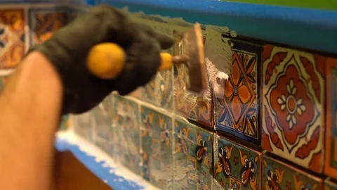 Closeup of spatula float pressing wet grout in between colorful tiles. Stock Footage 101434775