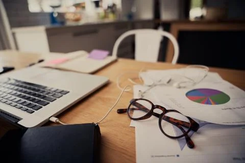 Closeup of spectacles on documents near laptop with connected earphones on Stock Photos