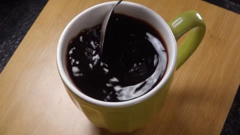 Closeup of Spoon Stirring Dark Coffee Inside Ceramic Mug on Wooden Table Video stock 340807082