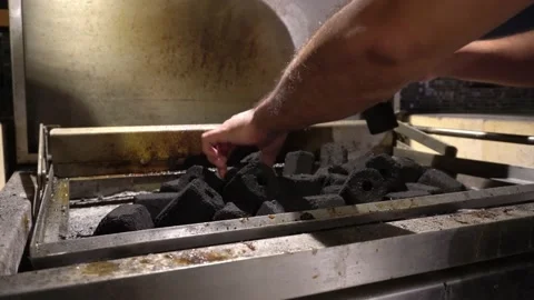 Closeup spreading a pile of coals on the grill and hands on the rooftop at night Vidéo 186220839