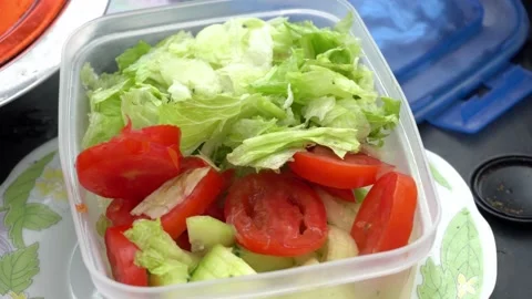 Closeup squeezing lemon juice over a lettuce and tomato salad and pouring table 動画素材 160089177