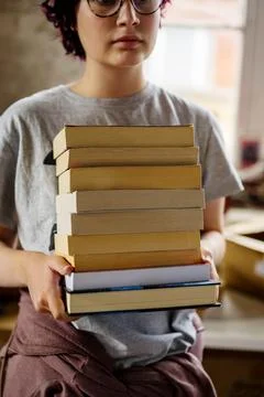 Closeup stack of books in hands of a teenage girl at book shop Stock Photos