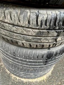 Closeup of stack of dirty car tires on the ground with selective focus on f.. Stock Photos