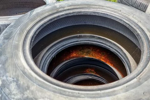 Closeup on stack of old and used tires with rain water and become breeding place Foto stock