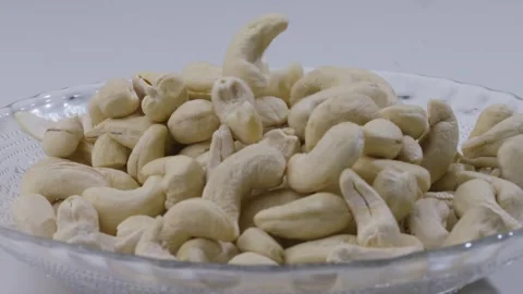 Closeup static shot of  cashew falling into the empty plate on the table Stock Footage 287850169