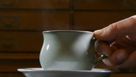 Closeup of a steaming cup of hot drink in a saucer. Stock Footage 108849812