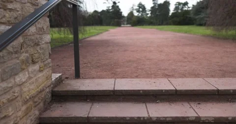 Closeup of steps in a park covered in greenery under a cloudy sky shot in 4 Stock Footage 162432215