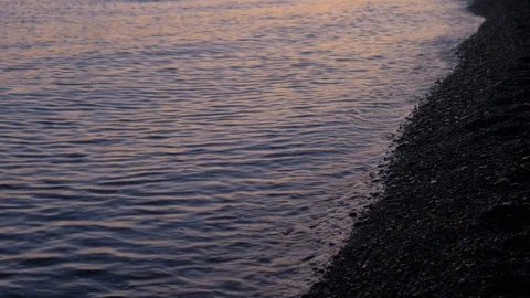 Closeup of a stone beach at evening. Close-up wave washes the shore at sunset Stock Footage 109156915