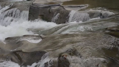Closeup. The stream flows water with brown rocks. Stock Footage 97822671