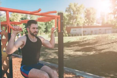 Closeup of strong athlete doing pull-up on horizontal bar.Mans fitness with blue Stockfoto's