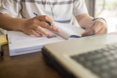 Closeup of student hand using pen while studying on workbook Stock Photos