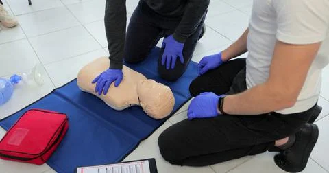 Closeup of students practicing CPR chest compression on teen dummy. Stockfoto's